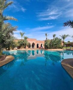 uma grande piscina com palmeiras e um edifício em Riad dar lamia em Marrakech