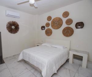 a white bedroom with a bed and plates on the wall at Paulas Suites in Ixtapa