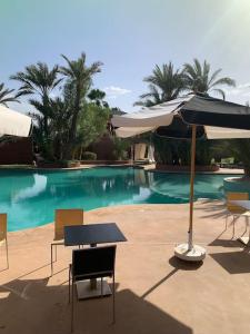 uma mesa com um guarda-sol ao lado de uma piscina em Riad dar lamia em Marrakech