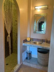 uma casa de banho com um lavatório e um chuveiro com um espelho. em Riad dar lamia em Marrakech