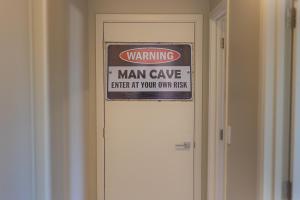 um sinal de caverna homem na porta de um quarto em Luxury Spa, Outdoor Fireplace & Games Room - Sleeps 10, 18 mins from CHC Airport em Prebbleton