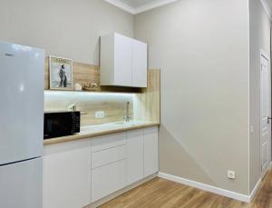 a kitchen with white cabinets and a microwave at ЖК Homeland EXPO 1 комн in Taldykolʼ
