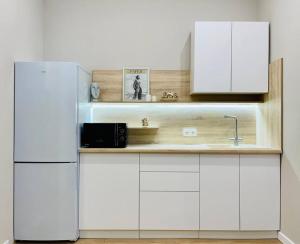 eine Küche mit weißen Schränken und einem Kühlschrank in der Unterkunft ЖК Homeland EXPO 1 комн in Taldykolʼ