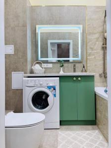 ein Badezimmer mit einer Waschmaschine und einem Spiegel in der Unterkunft ЖК Homeland EXPO 1 комн in Taldykolʼ