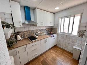 a kitchen with white cabinets and a wooden floor at Novelda Centro Habitaciones con baño privado y compartido , cocina y terraza in Novelda