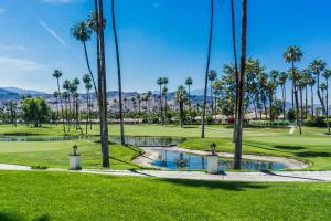 a golf course with palm trees and a pond at Rancho Mirage Condo in Rancho Mirage