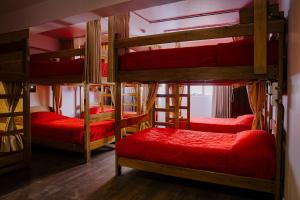 a room with four bunk beds with red sheets at Magar Hostel Bar in Cusco +121 photos