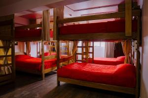a room with four bunk beds with red sheets at Magar Hostel Bar in Cusco