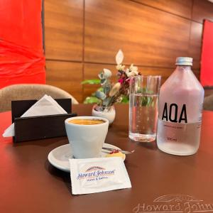 a table with a cup of coffee and a bottle of water at Howard Johnson La Cañada Hotel & Suites in Córdoba