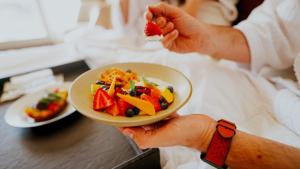 a person holding a plate of food with a fruit salad at Howard Johnson La Cañada Hotel & Suites in Córdoba