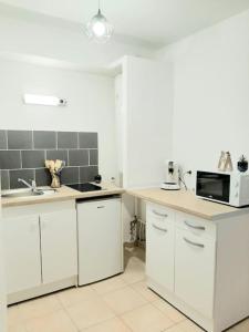 a kitchen with white cabinets and a microwave at Proche aéroport à pied, Le Rêve Rose. in Tillé