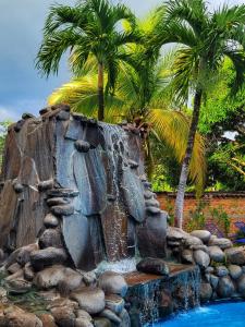a fountain with palm trees and a waterfall at El Tejado in Suchitoto