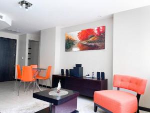 een woonkamer met oranje stoelen en een tafel bij Cómodo y amplio departamento con vista lateral al Rio! Bellinio, Puerto Santa Ana in Guayaquil