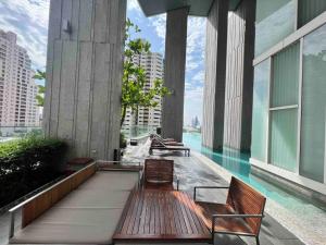 a pool on a building with chairs and a view of a city at Expansive Modern - BTS Phrom Phong - Ultra Fast WiFi in Khlong Toei