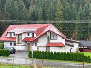 uma casa com um telhado vermelho num parque de estacionamento em Penzión Hruboš em Habovka