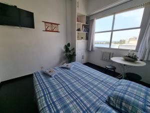 1 dormitorio con cama, mesa y ventana en Front Ocean Copacabana, en Río de Janeiro