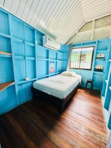 um quarto azul com uma cama e uma janela em Surf Paradise em Santa Teresa