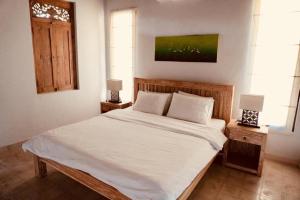 - une chambre avec un lit avec des draps blancs et 2 lampes dans l'établissement Matahari House, à Ubud