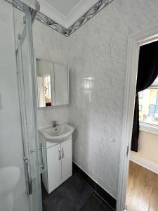 y baño con lavabo y espejo. en WIllesden Lodge Guest House, en Londres