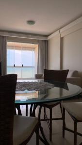 uma sala de estar com uma mesa de vidro e cadeiras em Apartamento Frente Mar em Vila Velha