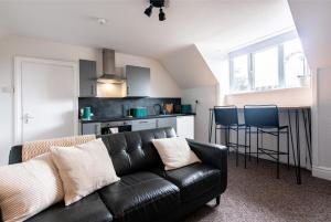 een woonkamer met een zwarte leren bank en een keuken bij Radbourne Apartments in Derby