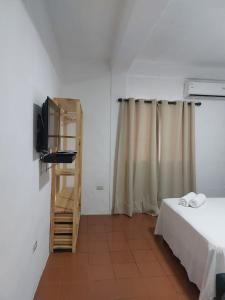 um quarto com uma cama, uma televisão e uma escada em Posada Restaurant La Guaricha em Catia La Mar