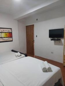 a bedroom with a white bed and a flat screen tv at Posada Restaurant La Guaricha in Catia La Mar
