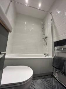 a white bathroom with a toilet and a bath tub at Spacious 1-Bed Apt in Stretford in Manchester