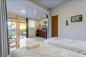 1 dormitorio con 1 cama blanca y cocina en Studio aconchegante a 130m do mar TOCA152, en Florianópolis