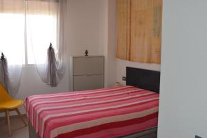 1 dormitorio con 1 cama con manta de rayas roja y blanca en Serena Moncofa, en Moncófar
