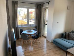 a living room with a table and a blue couch at Apartmán "DUNAJ" private parking - klimatizácia in Šamorín