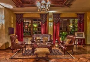 a living room with leather furniture and a chandelier at Hotel Doupiani House in Kalabaka