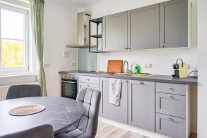 eine Küche mit weißen Schränken und einem Tisch mit Stühlen in der Unterkunft revLIVING Apartment Quintus Baden City Center in Baden