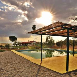 a swimming pool with an umbrella and the sun at Casa Rural Huerta Los Caños in Bienvenida