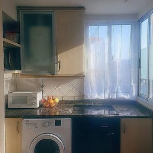 a kitchen with a washing machine and a microwave at Amplio apartamento in Puebla de Farnals