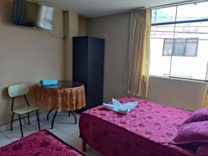 1 dormitorio con 2 camas, mesa y ventana en Hospedaje San Camilo Tacna, en Tacna