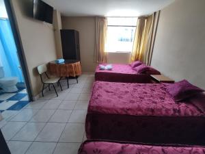 Habitación de hotel con 2 camas y mesa en Hospedaje San Camilo Tacna, en Tacna