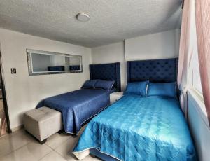 two beds in a bedroom with blue sheets at Apartamento en el Peñón - Oeste in Cali