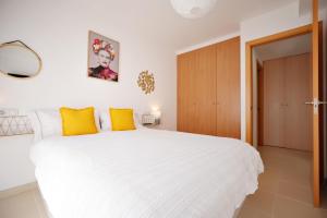 1 dormitorio con 1 cama blanca grande con almohadas amarillas en Apartamento dúplex Catalunya, en Sant Antoni de Calonge