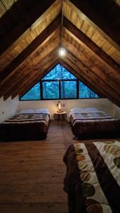 a attic room with three beds and a window at Cabaña Luna Encantada in Mazamitla