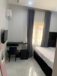 um quarto com uma cama, uma cadeira e uma janela em Bott Extended Stay em Abuja