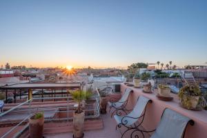 a rooftop patio with chairs and a view of the city at Riad Dar Azal in Marrakesh