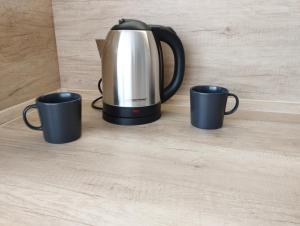 a tea kettle and three coffee mugs on a table at New apartman Sali in Galanta
