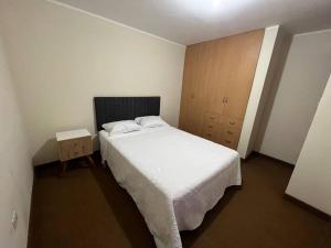 Elegante Apartamento cerca de la Plaza de Armas de Arequipa في أريكيبا: غرفة نوم بسرير أبيض وخزانة خشبية