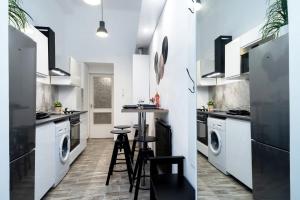 a kitchen with white cabinets and a bar with stools at Welcoming modern apartment in the center in Budapest