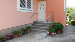 a pink house with a white door and some potted plants at Apartment Marica in Brodarica