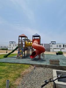 um parque infantil com um escorrega vermelho e uma escalada em Departamento de Playa (con piscina propia) en km 107 Asia, Lima em Asia