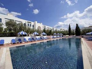 a swimming pool with blue chairs and a building at Diar Lemdina Hotel in Hammamet