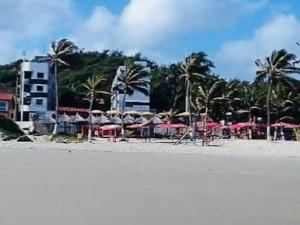 uma praia com guarda-sóis, mesas e palmeiras em Edifício Ocean garden em São Luís