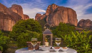a table with wine glasses and bowls of food at Hotel Doupiani House in Kalabaka